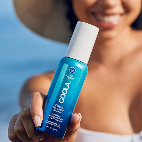 Woman holding COOLA's Classic Face Mist Sunscreen