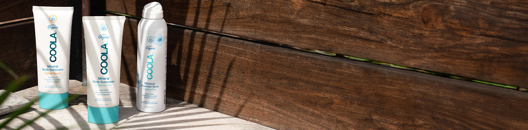 COOLA mineral sunscreen lotions and sprays on a wooden surface