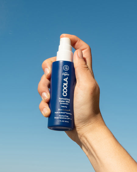 COOLA Refreshing Water Mist being sprayed against sky background