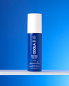 COOLA Refreshing Water Mist sitting on shelf against blue background