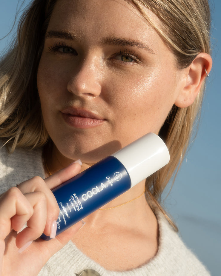 Woman holding Refreshing Water Mist to face with sky background