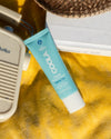 COOLA Classic Face Sunscreen Lotion Fragrance-Free SPF 50 laying down on yellow beach towel