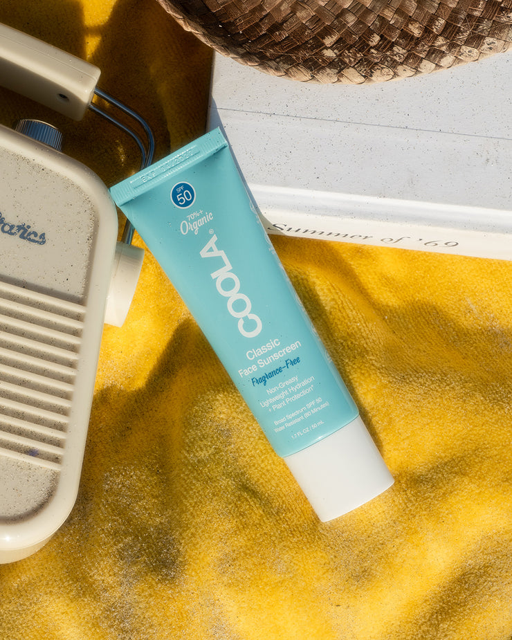 COOLA Classic Face Sunscreen Lotion Fragrance-Free SPF 50 laying down on yellow beach towel