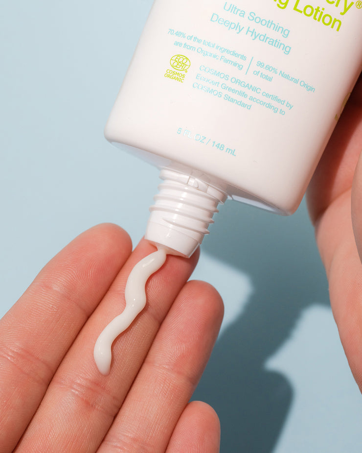 Close-up of COOLA Radical Recovery Moisturizing Lotion being dispensed in hand with light blue background
