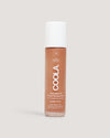 Coola bottle of golden brown sunscreen lotion on neutral background