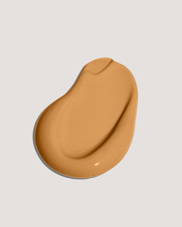 Golden brown sunscreen swatch on neutral background