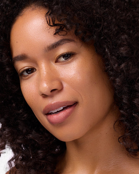 Close-up of a person with curly hair against a neutral background