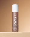 Coola Rosilliance Fresh Rose Tinted Moisturizer bottle on a beige background