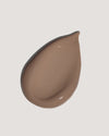 Dark brown tinted moisturizer formula on neutral background