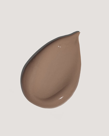 Dark brown tinted moisturizer formula on neutral background