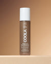 Coola Rosilliance Bronze Goddess Tinted Moisturizer standing up with a beige background