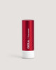 A red tube of COOLA Liplux Tinted Lip Balm with SPF 30, flavor Firecracker, standing upright on a beige background.