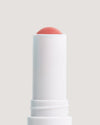 COOLA Nude Beach Mineral Liplux stick showing formula against a beige background.