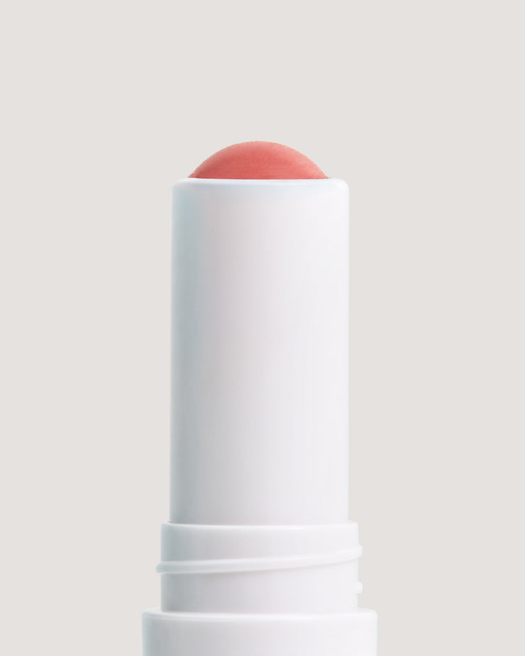 COOLA Nude Beach Mineral Liplux stick showing formula against a beige background.