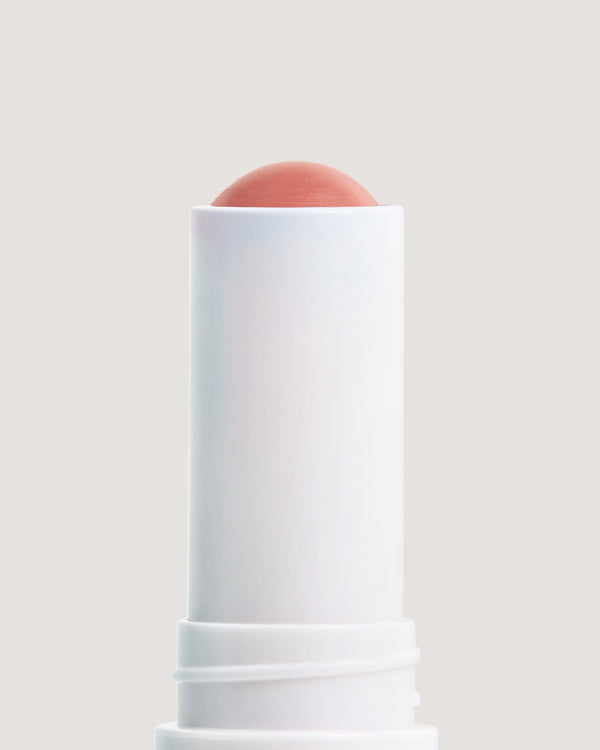 Close up of COOLA Skinny Dip Mineral Liplux formula against beige background.