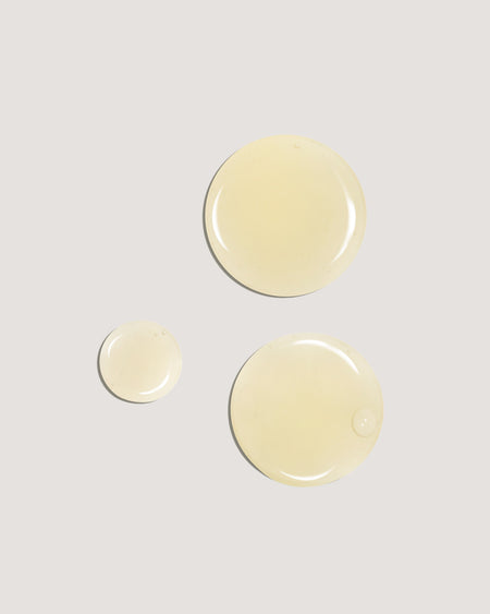 COOLA Sunless Tan Anti-Aging Face Serum formula drops on beige background.