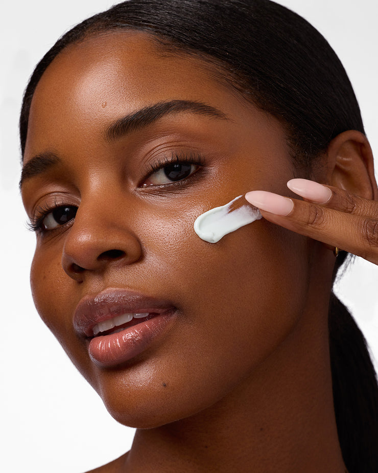 Woman applying COOLA Refreshing Water Cream to cheek