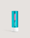 A stick of COOLA Tinted Liplux Lip Balm Sunscreen with a turquoise body and pink labeling.