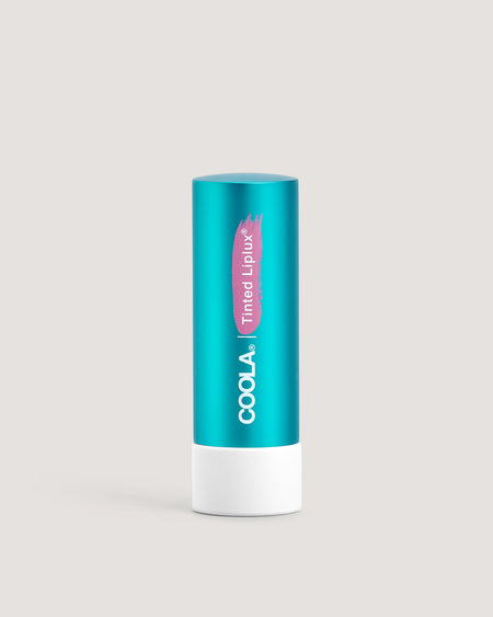 A stick of COOLA Tinted Liplux Lip Balm Sunscreen with a turquoise body and pink labeling.