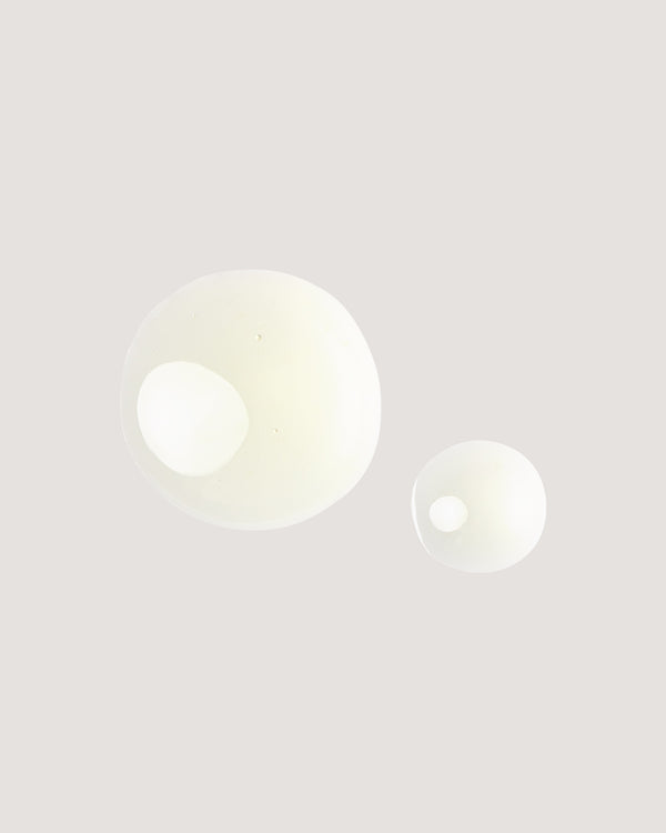 COOLA Liplux Hydrating Lip Oil formula drops against beige background.