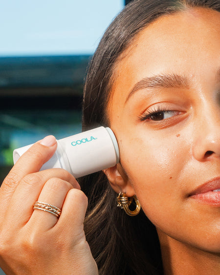 Woman applying COOLA Refreshing Water Hydration Stick to cheek