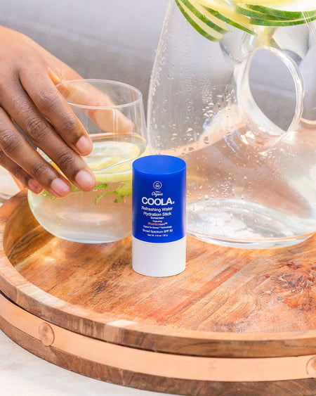 COOLA Refreshing Water Hydration Stick sitting on patio table