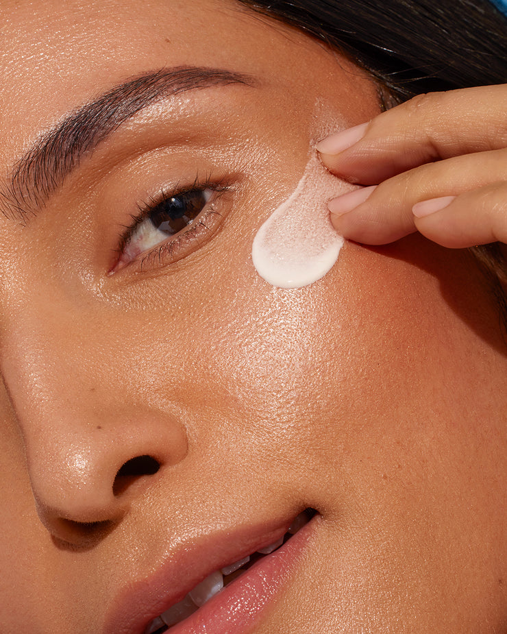 Close-up of woman applying COOLA Dew Good Illuminating Serum SPF 30 to cheek