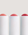 Close-up of COOLA lip products against beige background.