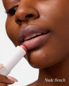 Close-up of woman applying COOLA Mineral Tinted Liplux Nude Beach against a white background.