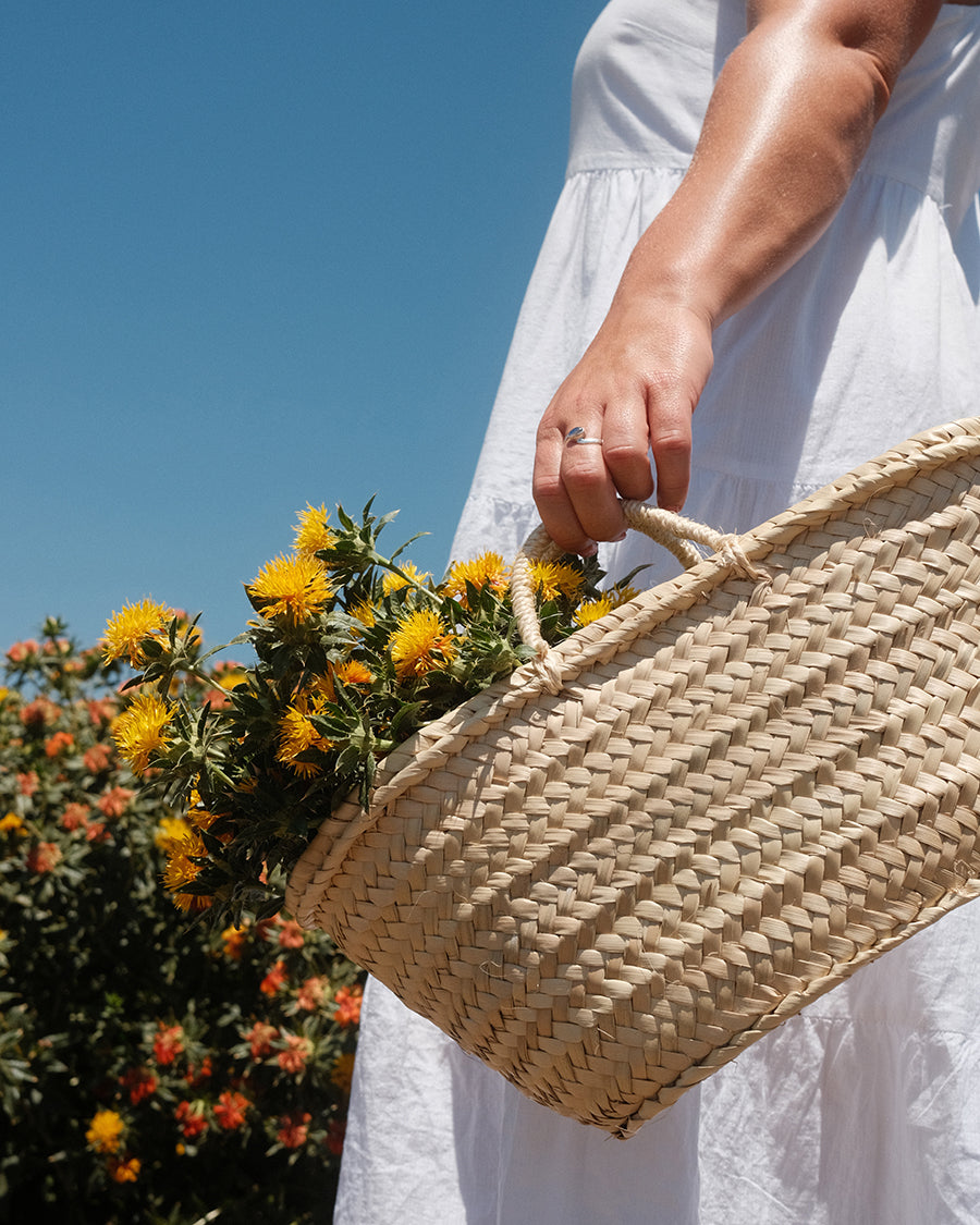 Woman in white dress holding basket with safflowers