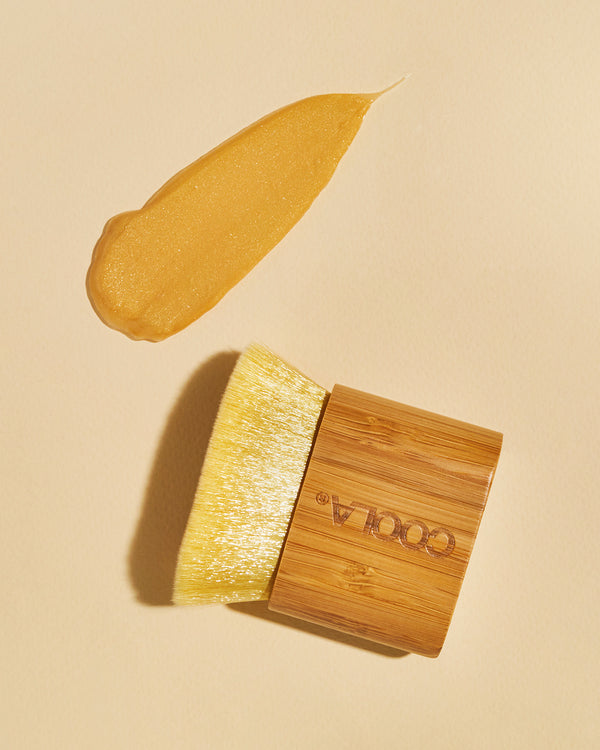 Bamboo brush sitting on an background with brown formula swatch next to it