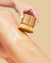 Person applying tinted formula to leg with small bamboo brush