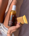 Person holding brown bottle with bamboo brush