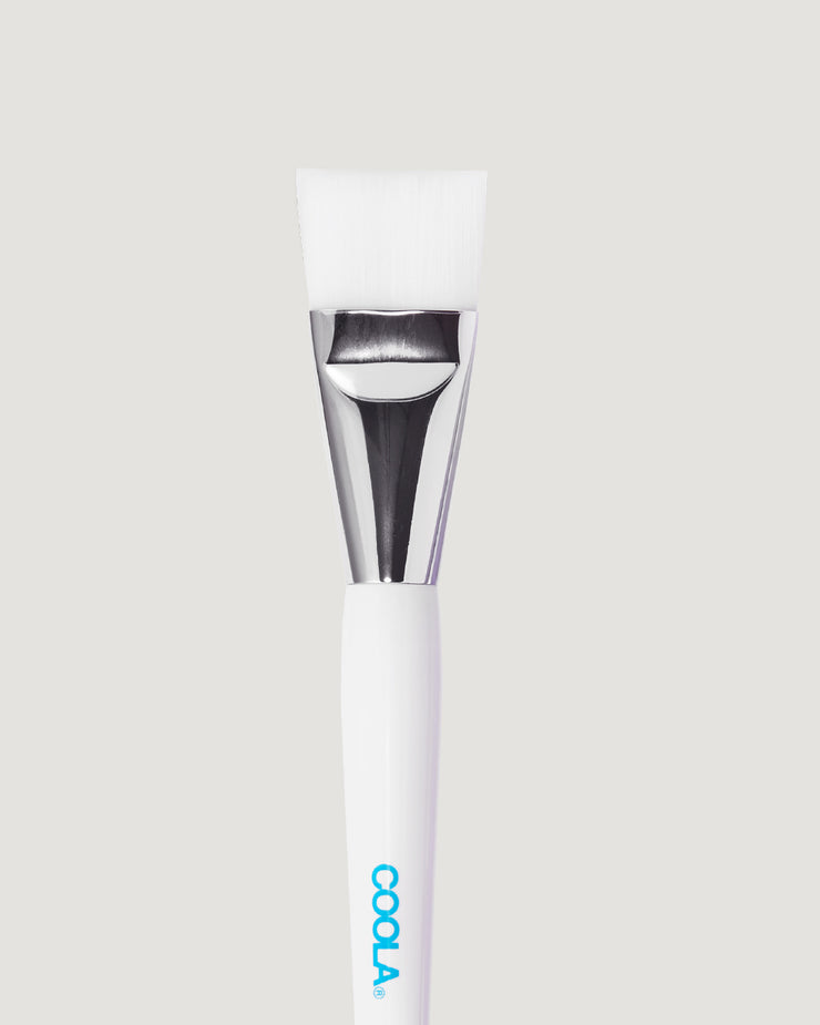 White facial brush against a beige background