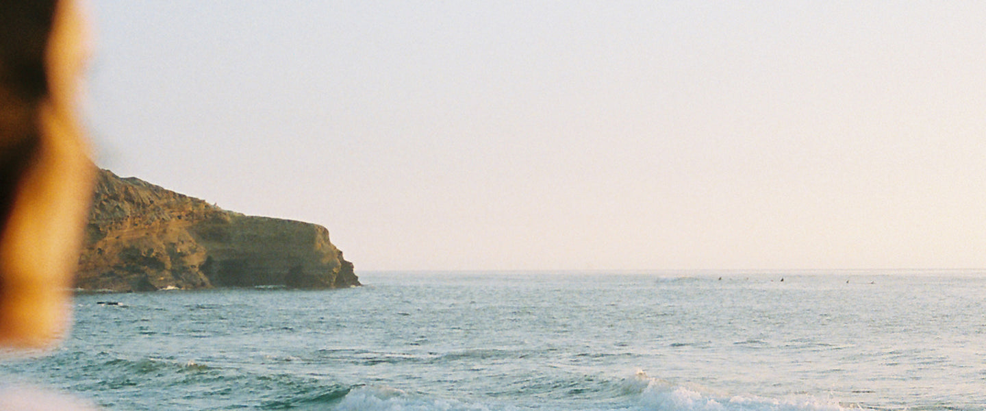 View of ocean and sky horizon line with cliff in distance