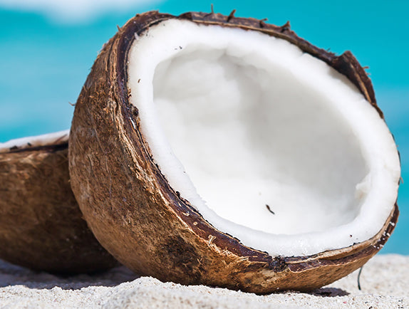Coconut cracked open on a beach with blue background