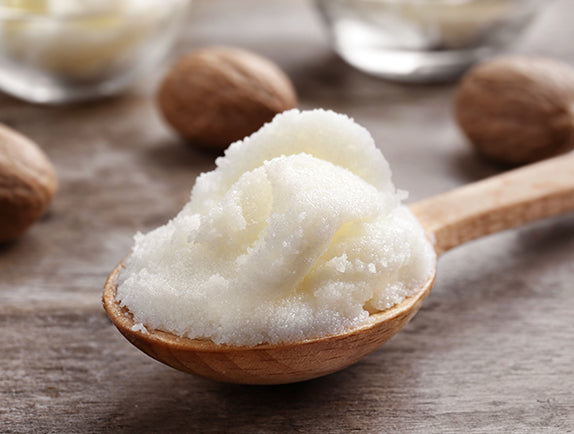 Organic shea butter in wooden spoon on wooden table