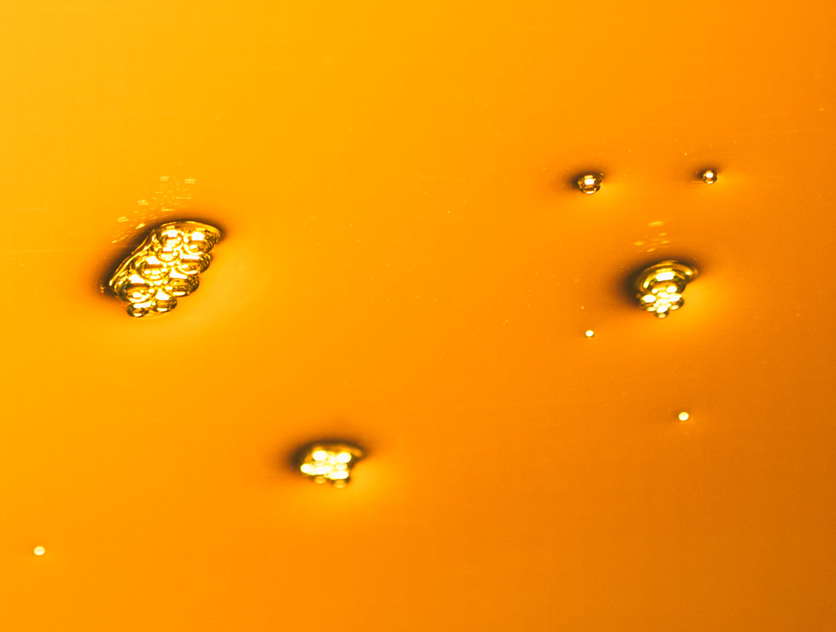 Macro image of a pool of yellow sunscreen oil with a golden hue