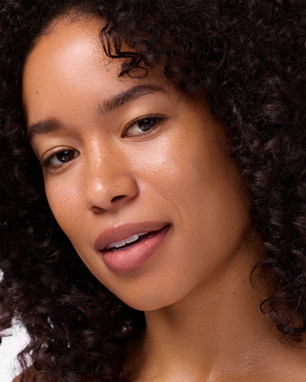 Close-up of a person with curly hair against a neutral background