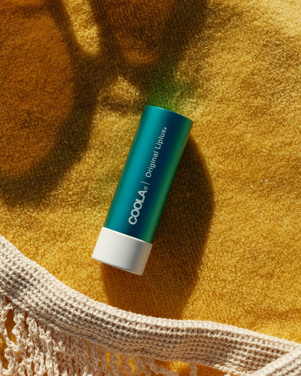 COOLA Original Liplux sitting on yellow towel 