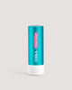 A stick of COOLA Tinted Liplux Lip Balm Sunscreen with a turquoise body and pink labeling.