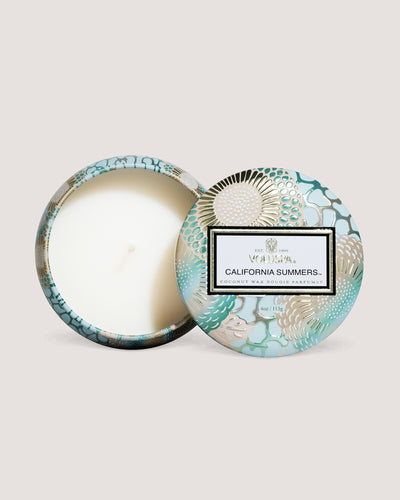 California Summers candle mini tin on its side showing wick in front of beige background