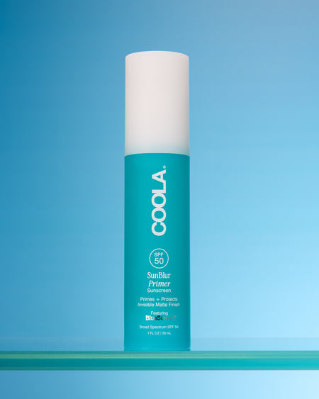 Coola sunscreen bottle on a blue background