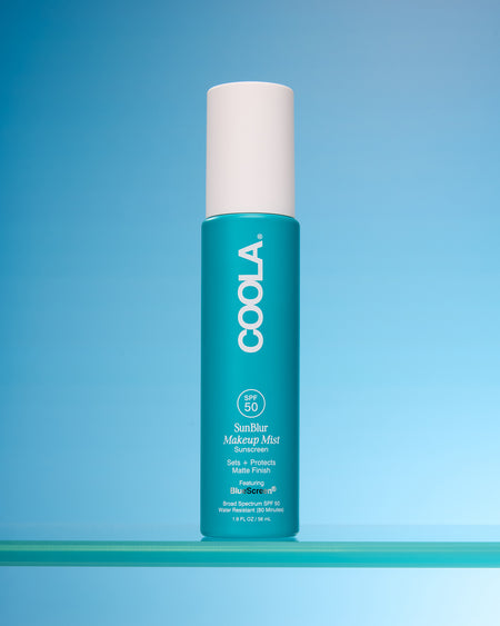 Coola Sunscreen Makeup Mist bottle on a blue background