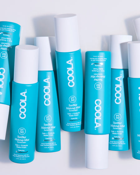Multiple bottles of Coola sunscreen products on a white background