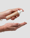 COOLA Rosilliance® Tinted Moisturizer - Sun Kissed bottle dispensing tinted moisturizer into an open hand for a natural sun kissed glow and everyday SPF Skin Care