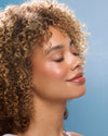 Close-up of a woman with curly hair against a blue background