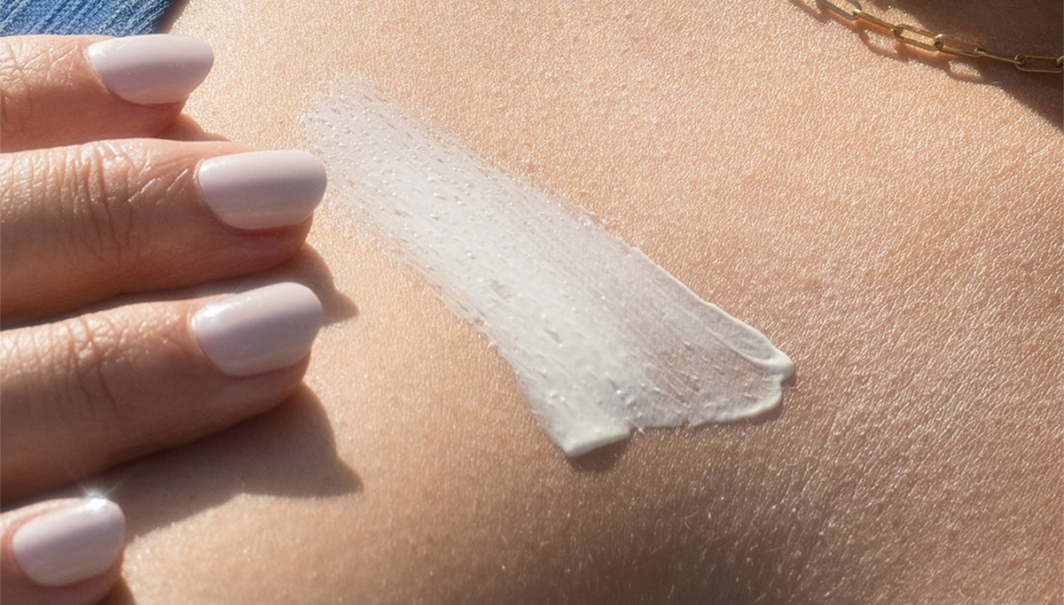 Close-up of woman applying sunscreen lotion to chest.