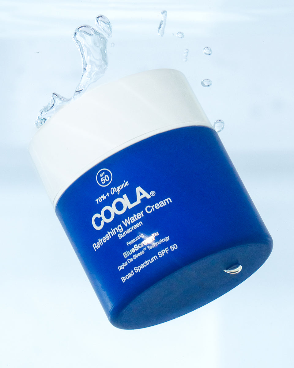 Jar of COOLA Refreshing Water Cream SPF 50 dropped in water, blue jar 
