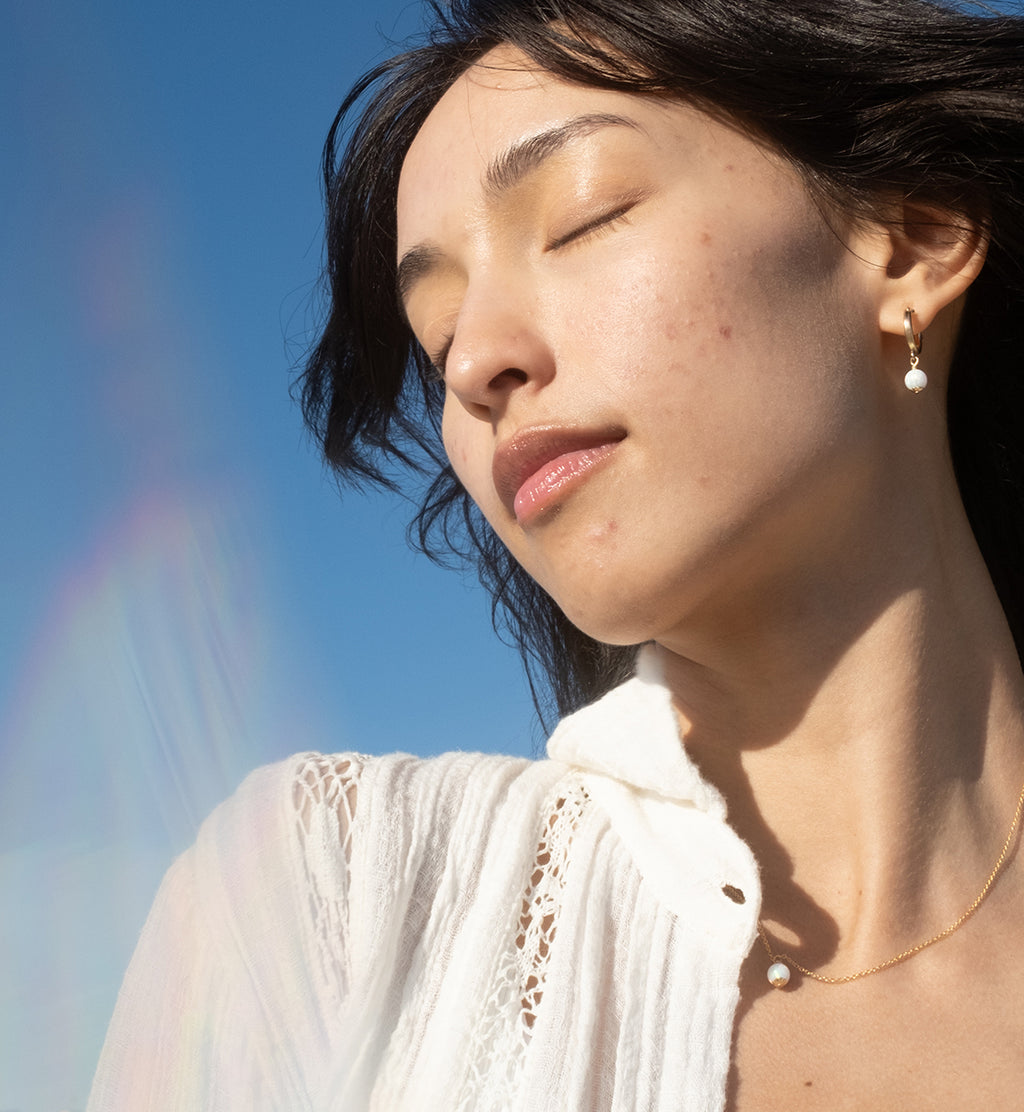 Woman closing eyes relaxing into wind with blue sky background